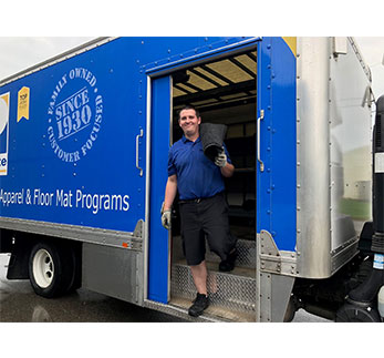 Plymate service rep unloading floor mats from the truck